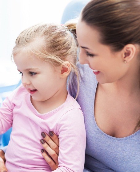 Mother holding child during dental checkup and teeth cleaning visit