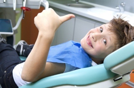Child giving thumbs up during dental checkup and teeth cleaning visit
