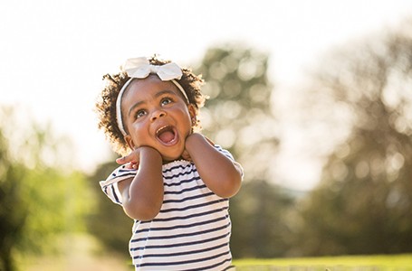 a toddler smiling and having fun while playing in a park