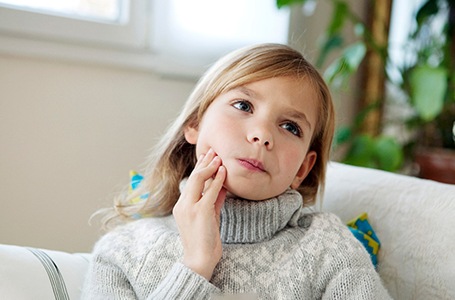 a child holding their mouth because they have a toothache