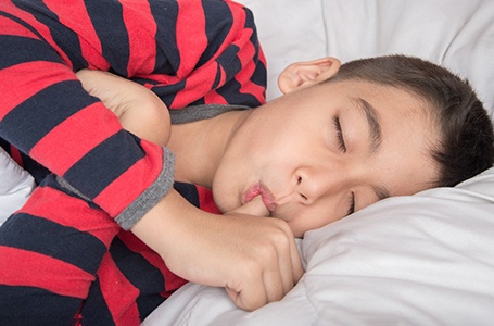an older child sucking their thumb as they sleep