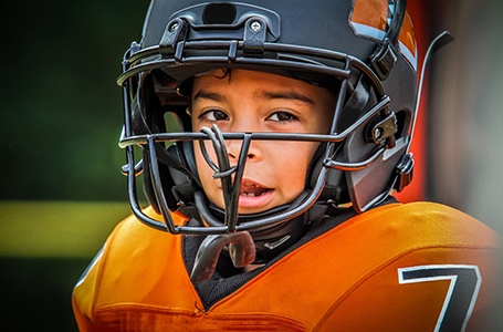 child playing football with a mouthguard attached to their helmet