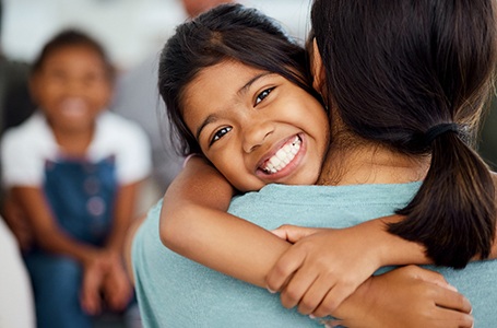 a smiling child hugging their mom