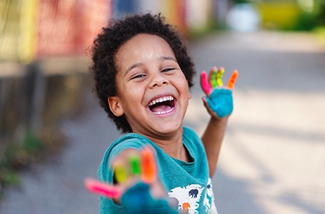 a child with paint on their hands laughing and having fun