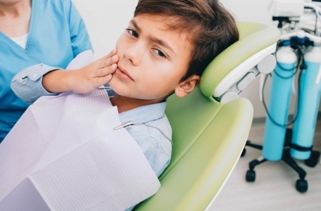 Child holding cheek before emergency dentistry
