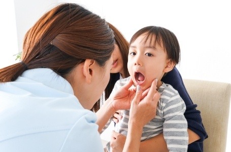Dentist examining child's smile for signs of a need for tooth extractions