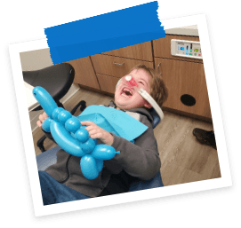 Laughing child holding balloon animal in Allen dental treatment room