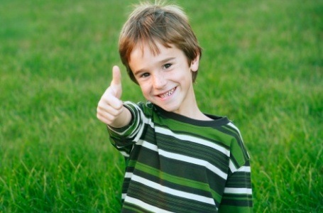 Child in need of nightguard giving thumbs up