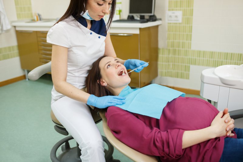 A young dentist working with a pregnant patient